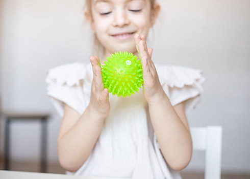 Criança brincando com bola sensorial.